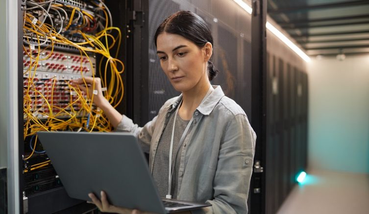 Waist,Up,Portrait,Of,Female,Network,Engineer,Connecting,Cables,In